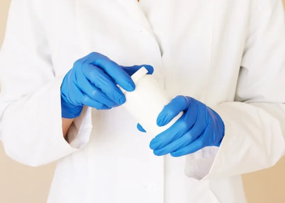 an image of someone wearing a white coat and blue healthcare gloves