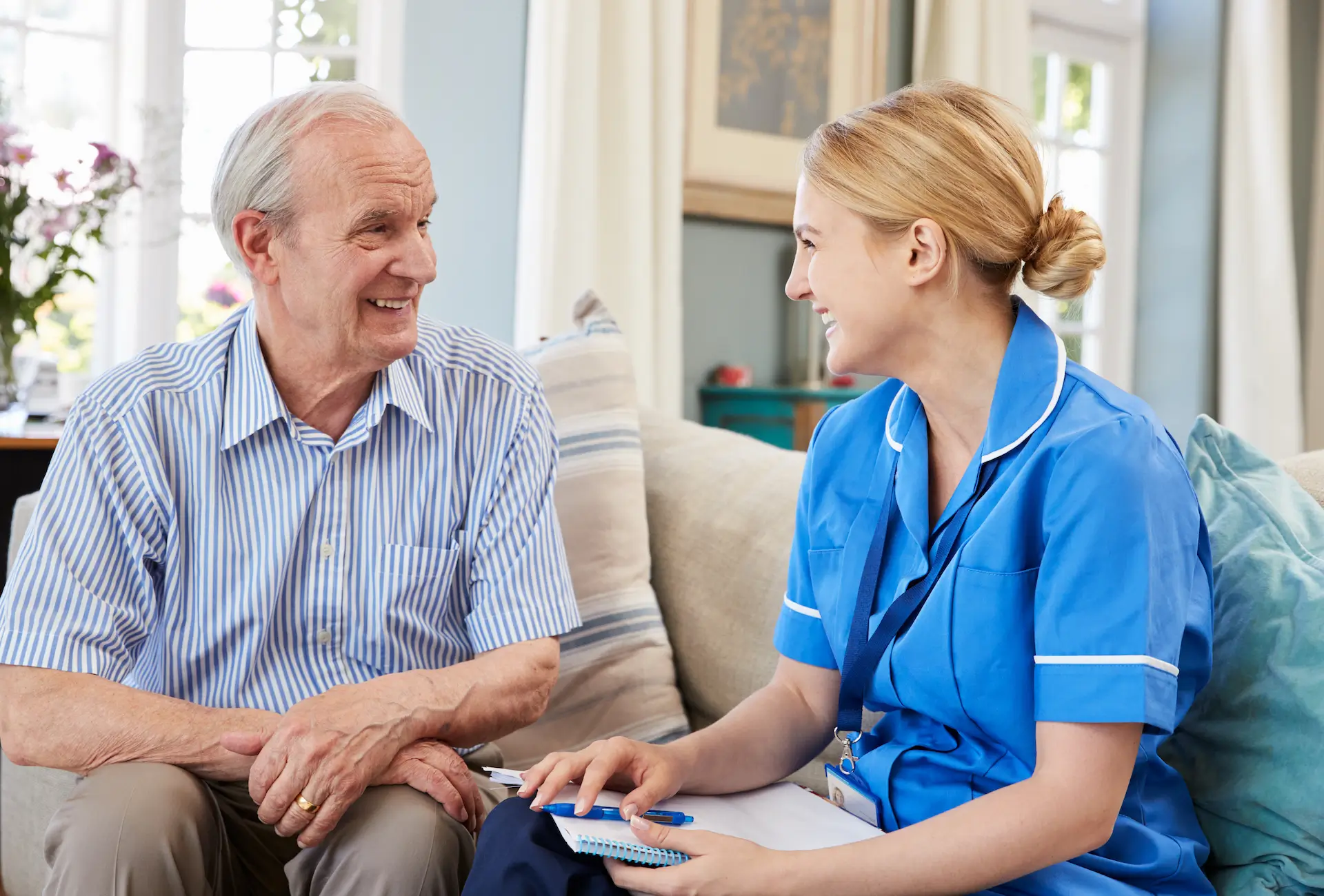 an image of a healthcare assistant talking to an older gentleman