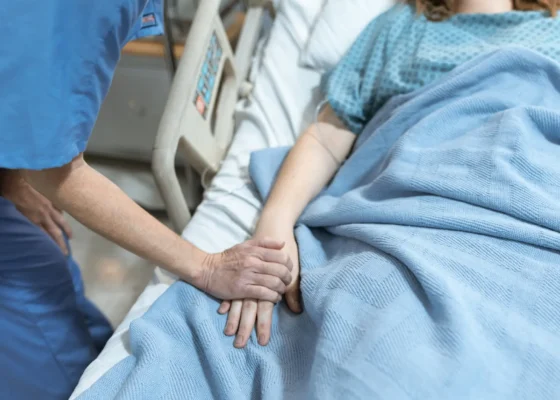 image of a healthcare worker comforting a patient in a hospital bed