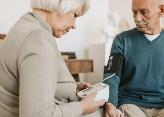 an image of a lady working in a care home checking the blood pressure of a gentleman