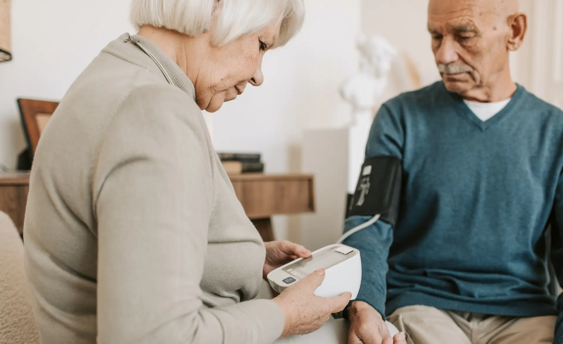 an image of a lady working in a care home checking the blood pressure of a gentleman