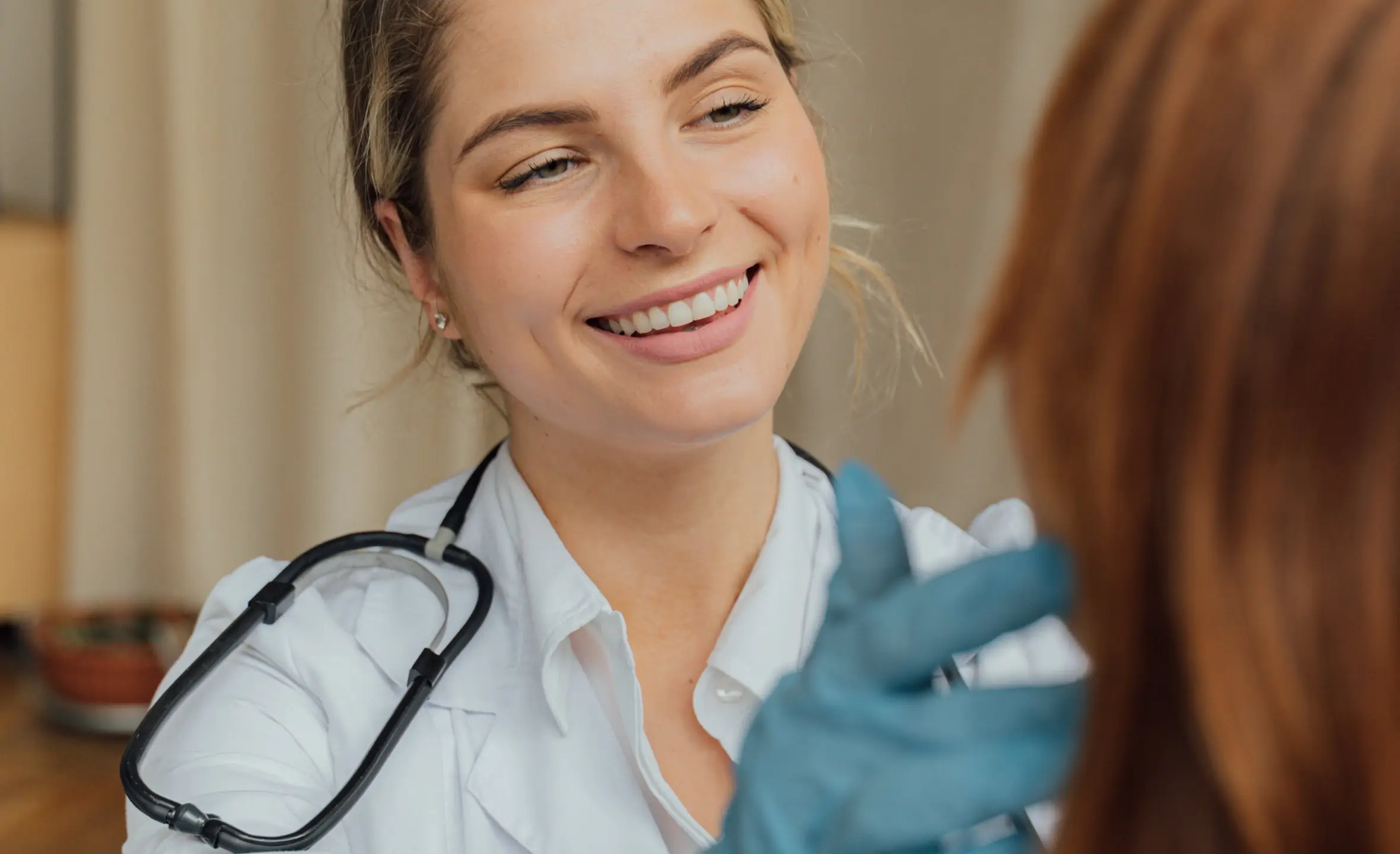 Image of a nurse examining a patient with a smile on her face