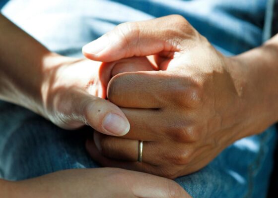 a close up image of the hands of a healthcare professional holding the hand of a patient