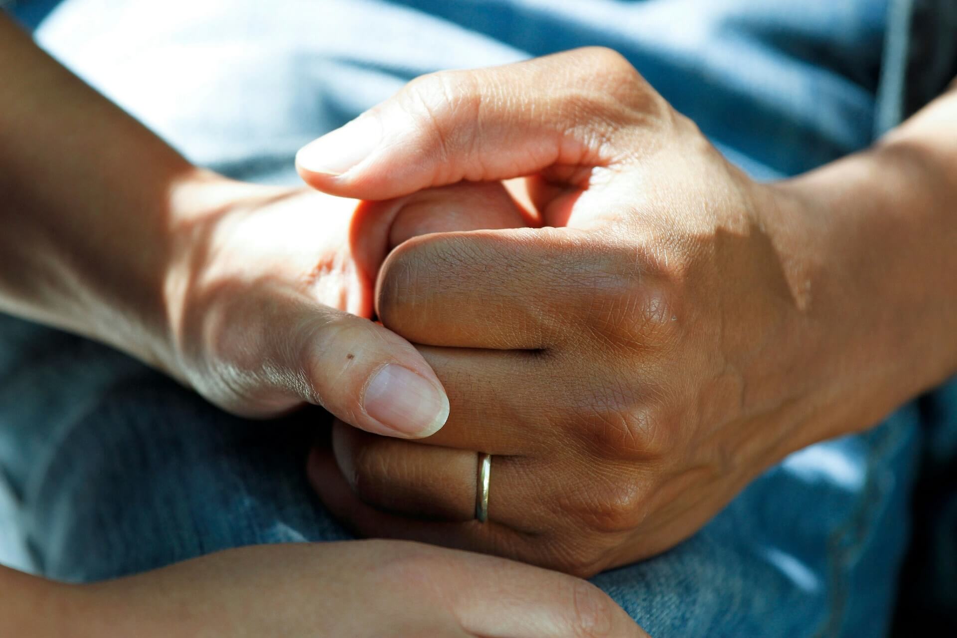 a close up image of the hands of a healthcare professional holding the hand of a patient
