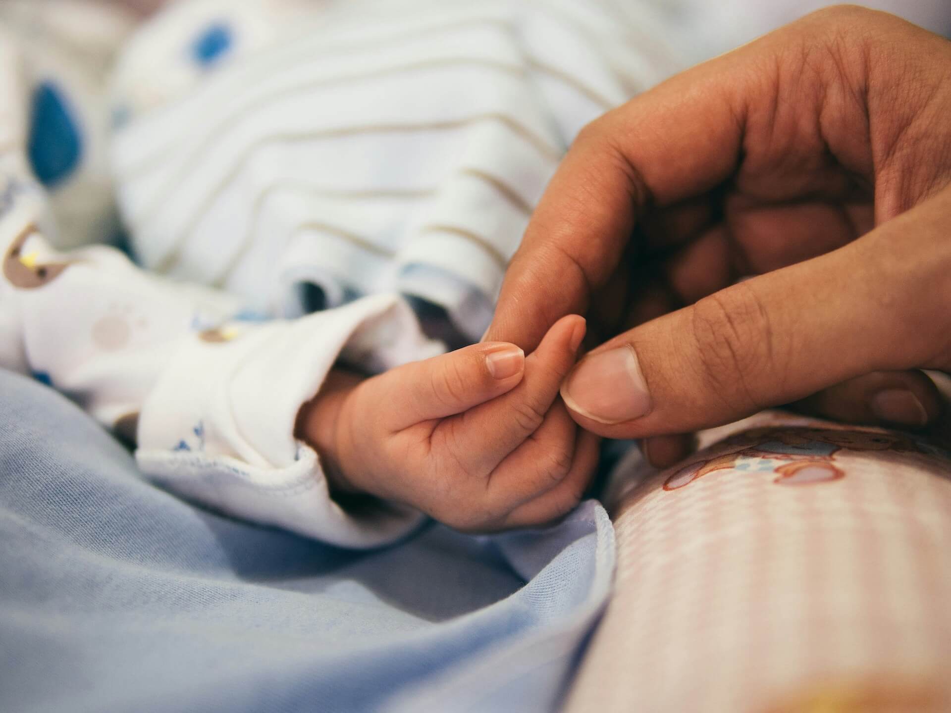 an image of the hand of a person and a new born baby for the midwife staffing page